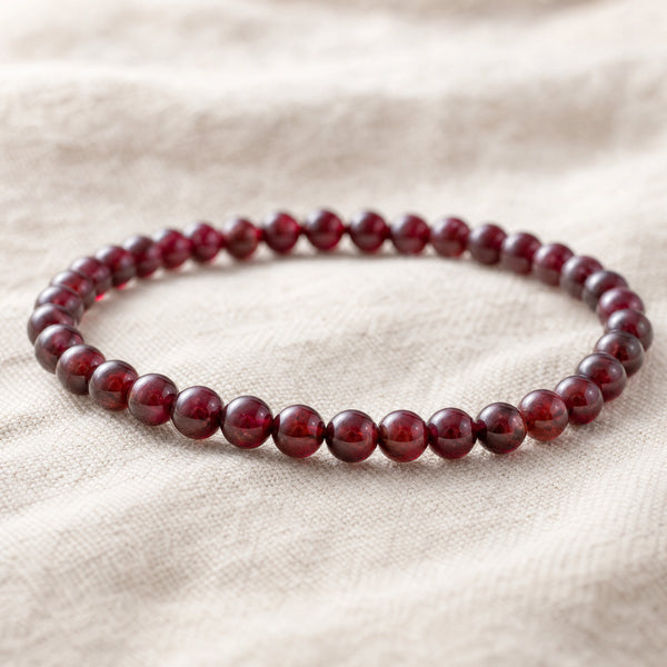 Close-up of the Garnet 4mm Round Bead Bracelet on natural linen