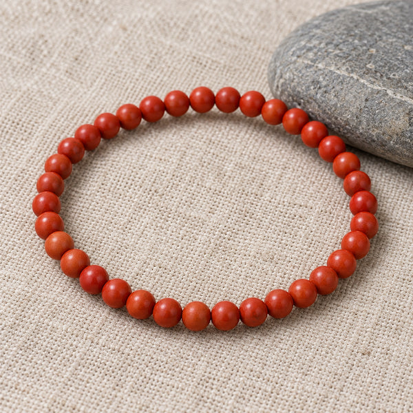 Soultheory Goldstone 4mm Round Bead Bracelet on beige linen beside a river pebble