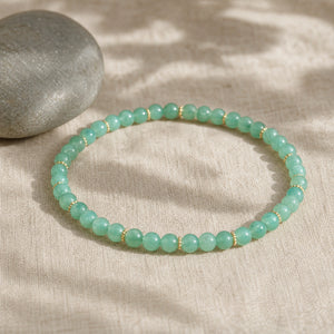 Soultheory Green Aventurine 4mm Bead Bracelet with Gold Spacers on beige linen beside a river pebble