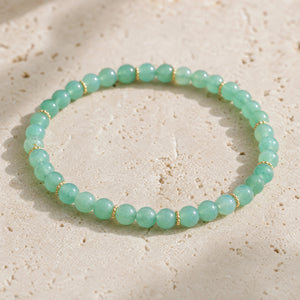 Close-up of the Green Aventurine 4mm Bead Bracelet with Gold Spacers on pale travertine