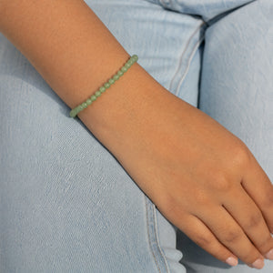 Woman wearing the Green Jade 4mm Round Bead Bracelet with blue denim