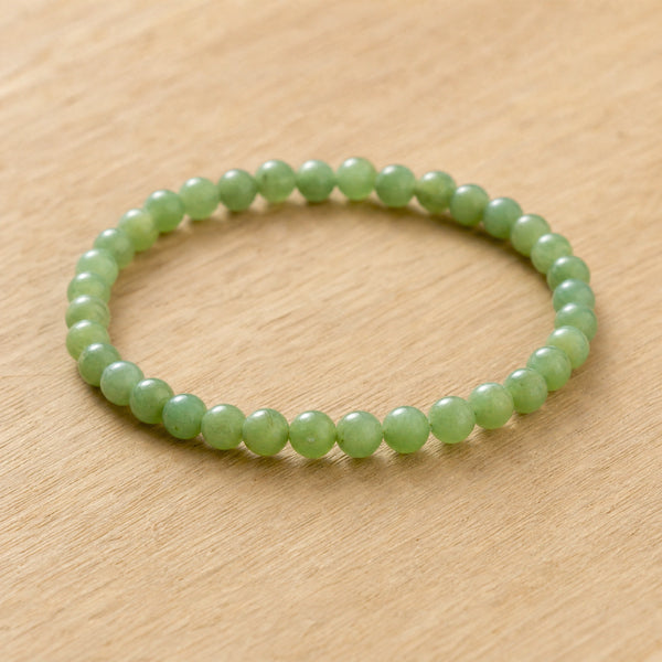 Close-up of the Green Jade 4mm Round Bead Bracelet on a light oak board