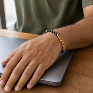 Man wearing the Hematite bracelet, at a wooden desk