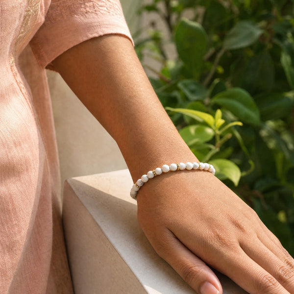 Woman wearing the Howlite 4mm Bead Bracelet with Gold Spacers with a peach cotton top