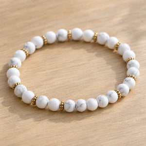 Close-up of the Howlite 4mm Bead Bracelet with Gold Spacers on a light oak board