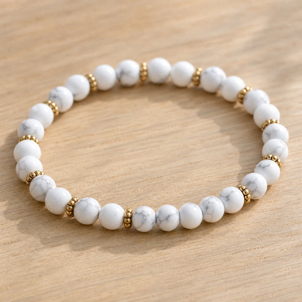 Close-up of the Howlite 4mm Bead Bracelet with Gold Spacers on a light oak board