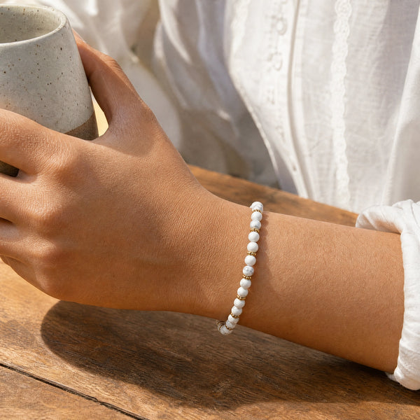 Woman wearing the Howlite bracelet, holding a ceramic coffee cup