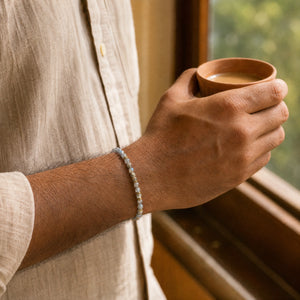 Man wearing the Labradorite bracelet, holding a cup of chai