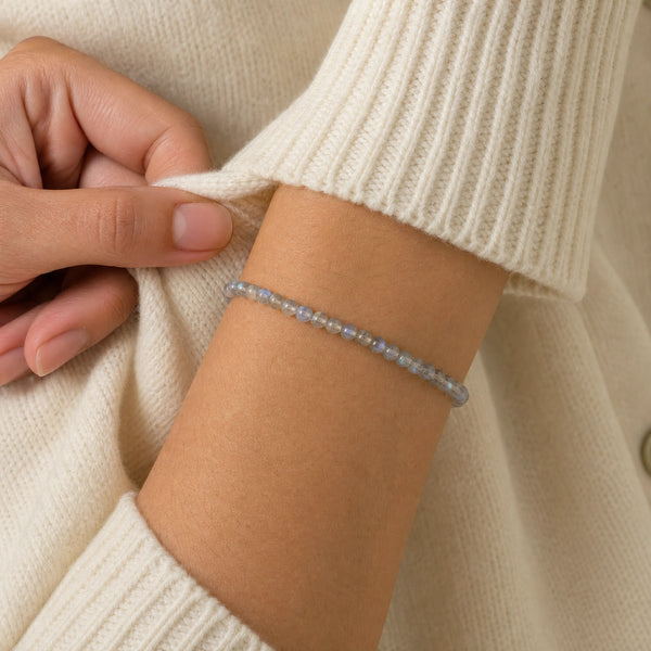 Woman wearing the Labradorite 4mm Round Bead Bracelet with a cream knit cardigan