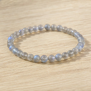 Close-up of the Labradorite 4mm Round Bead Bracelet on a light oak board
