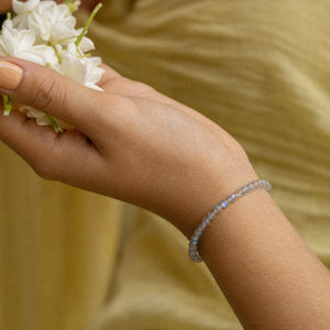 Woman wearing the Labradorite bracelet, holding fresh jasmine flowers