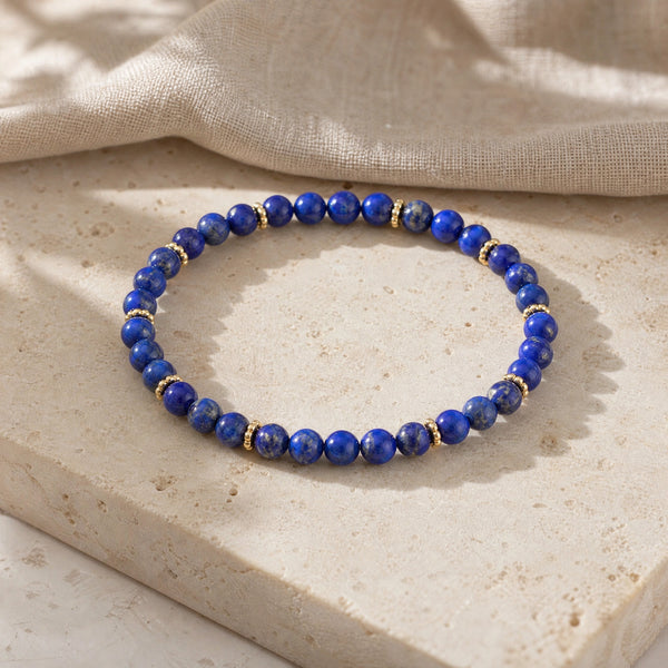 Soultheory Lapis Lazuli 4mm Bead Bracelet with Gold Spacers on a travertine slab and linen