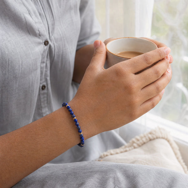 Woman wearing the Lapis Lazuli bracelet, holding a mug of tea