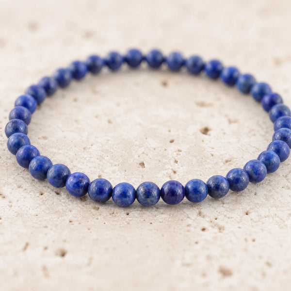 Close-up of the Lapis Lazuli 4mm Round Bead Bracelet on pale travertine