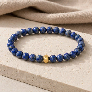 Soultheory Lapis Lazuli 6mm Bead Bracelet with Gold Accent on a travertine slab and linen