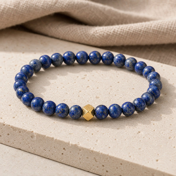 Soultheory Lapis Lazuli 6mm Bead Bracelet with Gold Accent on a travertine slab and linen