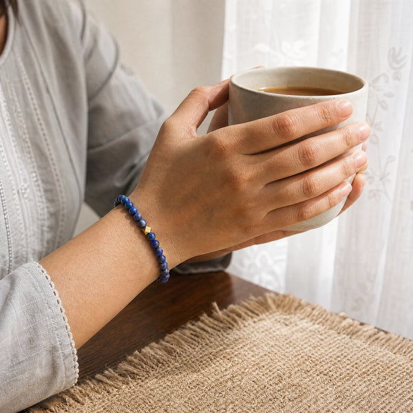 Woman wearing the Lapis Lazuli bracelet, holding a mug of tea