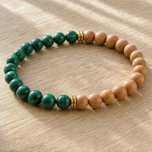 Close-up of the Malachite & Rosewood 6mm Bead Bracelet on a light oak board