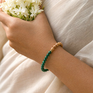 Woman wearing the Malachite bracelet, holding fresh jasmine flowers