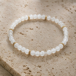 Close-up of the Moonstone 4mm Bead Bracelet with Gold Spacers on pale travertine