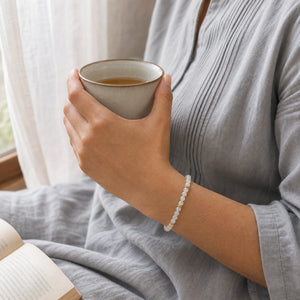 Woman wearing the Moonstone bracelet, holding a mug of tea