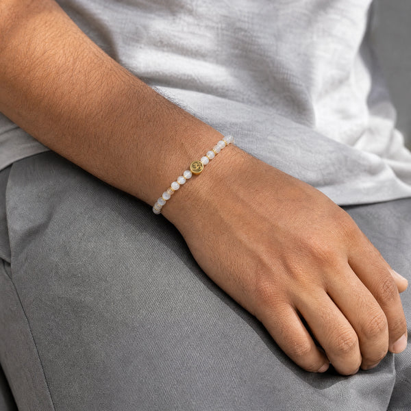Man wearing the Moonstone 4mm Bracelet with Om Charm with a grey t-shirt