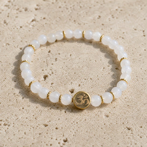 Close-up of the Moonstone 4mm Bracelet with Om Charm on pale travertine