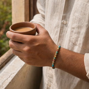 Man wearing the Multi Imperial Jasper bracelet, holding a cup of chai