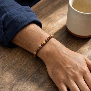 Man wearing the Picasso Jasper 6mm Bead Bracelet with Gold Accent with a navy cotton shirt