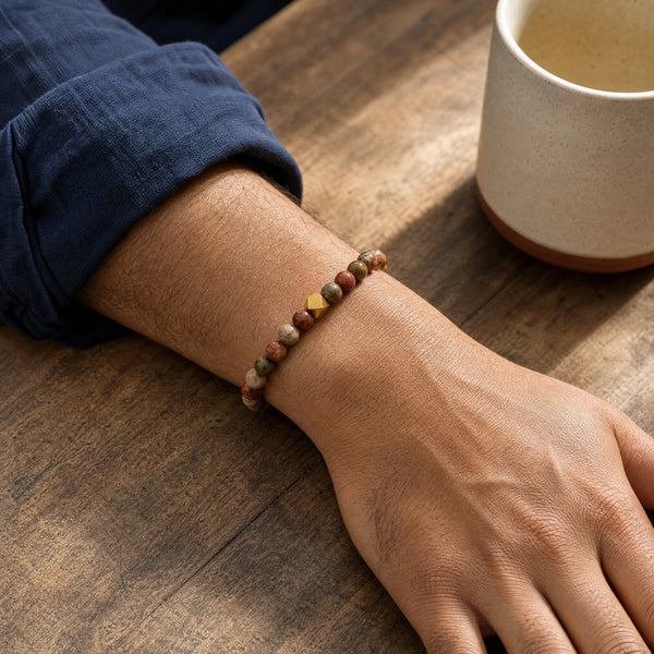 Man wearing the Picasso Jasper 6mm Bead Bracelet with Gold Accent with a navy cotton shirt