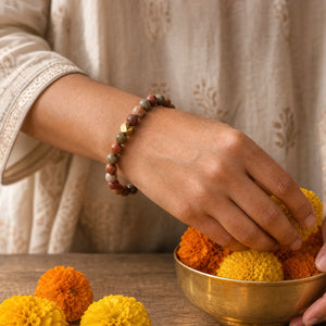 Woman wearing the Picasso Jasper bracelet, arranging marigold flowers