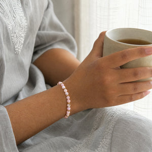 Woman wearing the Pink Opal bracelet, holding a mug of tea