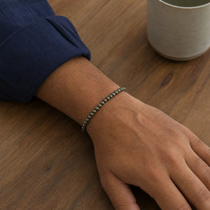 Man wearing the Pyrite 4mm Round Bead Bracelet with a navy cotton shirt
