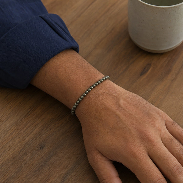 Man wearing the Pyrite 4mm Round Bead Bracelet with a navy cotton shirt