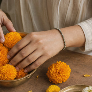 Woman wearing the Pyrite bracelet, arranging marigold flowers