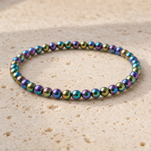 Close-up of the Rainbow Hematite 4mm Bead Bracelet on pale travertine