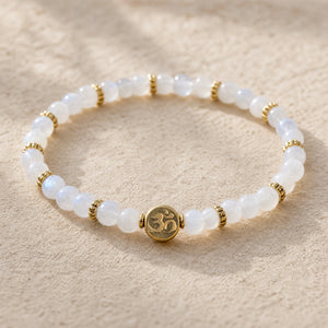 Close-up of the Rainbow Moonstone 4mm Bracelet with Om Charm on cream handmade paper