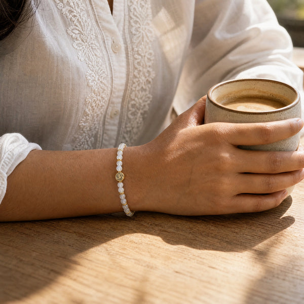 Woman wearing the Rainbow Moonstone bracelet, holding a ceramic coffee cup
