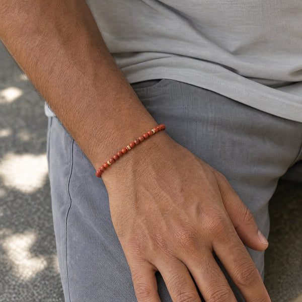 Man wearing the Red Jasper 4mm Bead Bracelet with Gold Spacers with a grey t-shirt