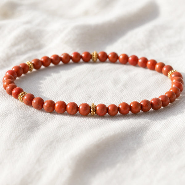 Close-up of the Red Jasper 4mm Bead Bracelet with Gold Spacers on white linen