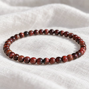 Close-up of the Red Tiger Eye 4mm Round Bead Bracelet on white linen