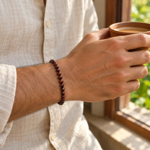 Man wearing the Red Tiger Eye bracelet, holding a cup of chai
