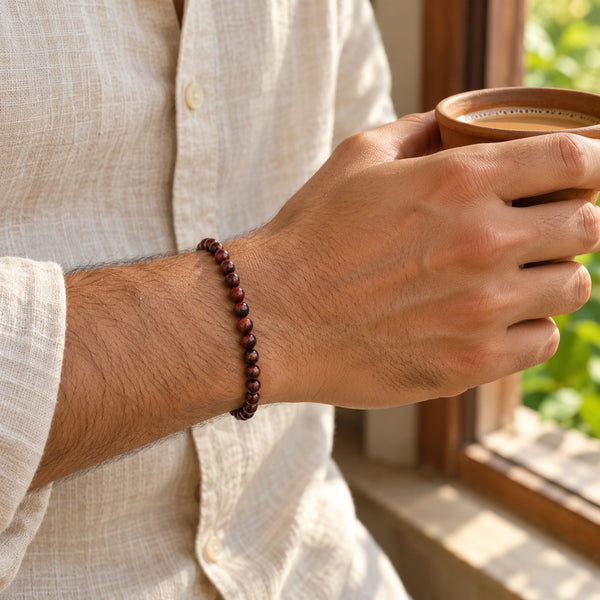 Man wearing the Red Tiger Eye bracelet, holding a cup of chai