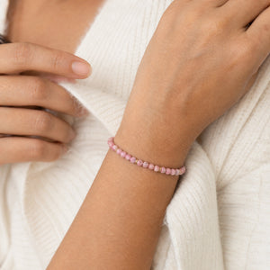 Woman wearing the Rhodonite 4mm Bead Bracelet with Gold Spacers with a cream knit cardigan