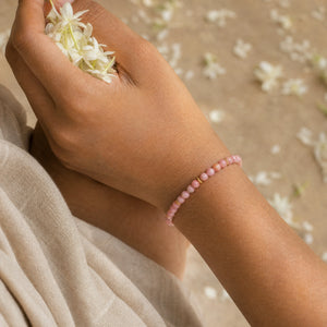 Woman wearing the Rhodonite bracelet, holding fresh jasmine flowers