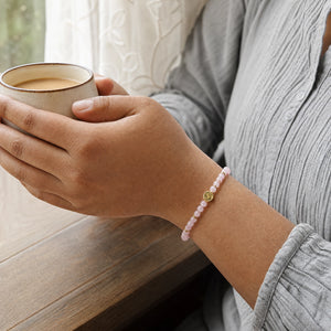 Woman wearing the Rose Quartz bracelet, holding a mug of tea