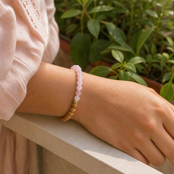 Woman wearing the Rose Quartz & Rosewood 6mm Bead Bracelet with a peach cotton top