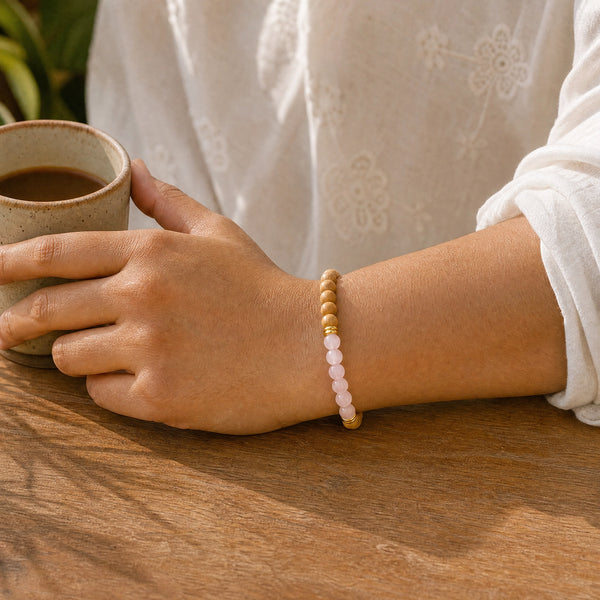 Woman wearing the Rose Quartz bracelet, holding a ceramic coffee cup