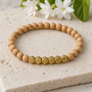 Soultheory Rosewood 6mm Bead Bracelet with Gold Accents on a limestone plinth with jasmine
