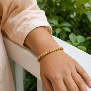 Woman wearing the Rosewood 6mm Bead Bracelet with Gold Accents with a peach cotton top